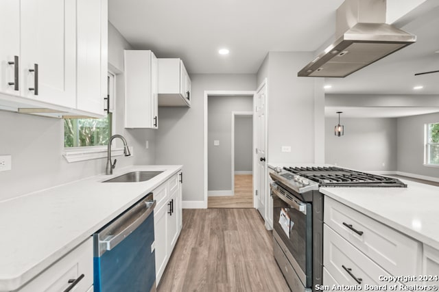 kitchen featuring light hardwood / wood-style floors, sink, white cabinets, wall chimney exhaust hood, and stainless steel appliances