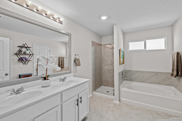 bathroom featuring a textured ceiling, vanity, plus walk in shower, and tile patterned floors