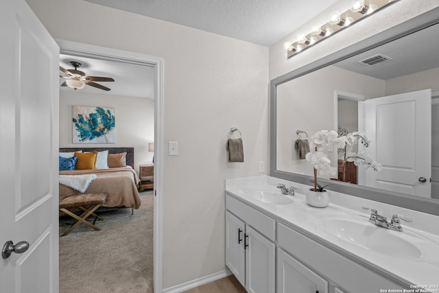 bathroom with ceiling fan, vanity, and a textured ceiling