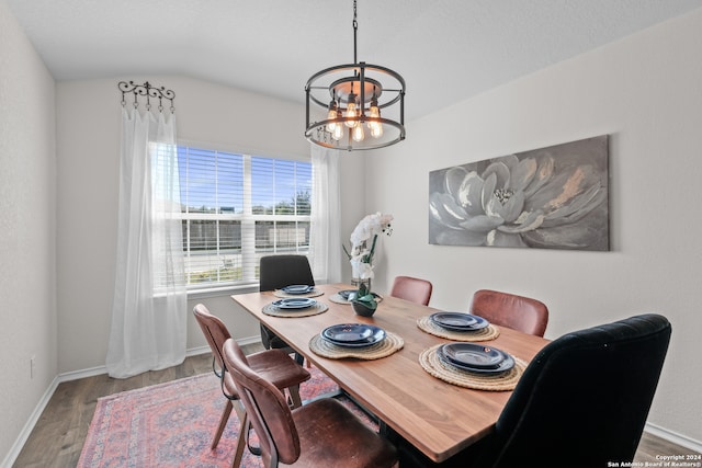 dining space featuring an inviting chandelier, lofted ceiling, and hardwood / wood-style flooring