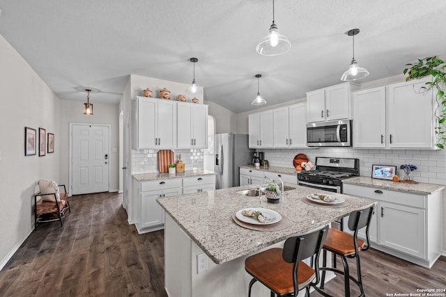 kitchen with an island with sink, stainless steel appliances, white cabinets, and dark wood-type flooring