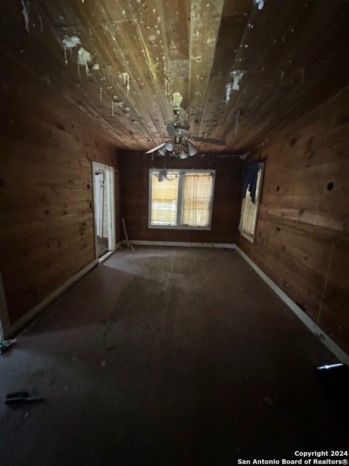 empty room with wood walls and ceiling fan