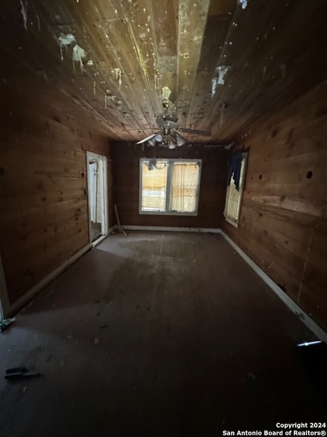 empty room with wood walls and ceiling fan