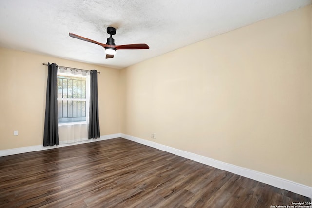 empty room featuring ceiling fan, dark wood-type flooring, and a textured ceiling