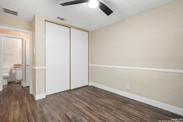 unfurnished bedroom with ceiling fan, connected bathroom, a closet, and dark hardwood / wood-style floors