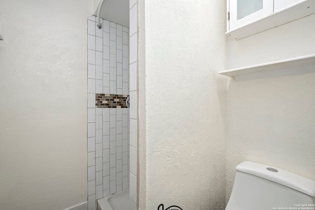 bathroom with tiled shower and toilet