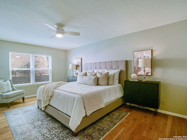 bedroom with hardwood / wood-style floors, ceiling fan, and a textured ceiling