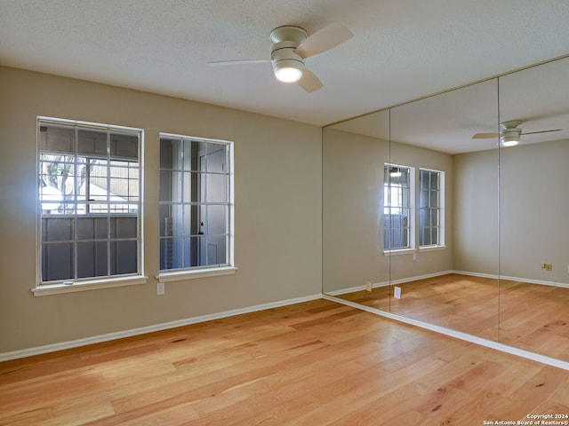 empty room with plenty of natural light, light hardwood / wood-style floors, a textured ceiling, and ceiling fan