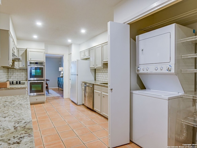 kitchen with backsplash, white cabinetry, stacked washer and dryer, and appliances with stainless steel finishes