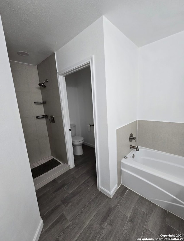 bathroom with toilet, wood-type flooring, a textured ceiling, and independent shower and bath