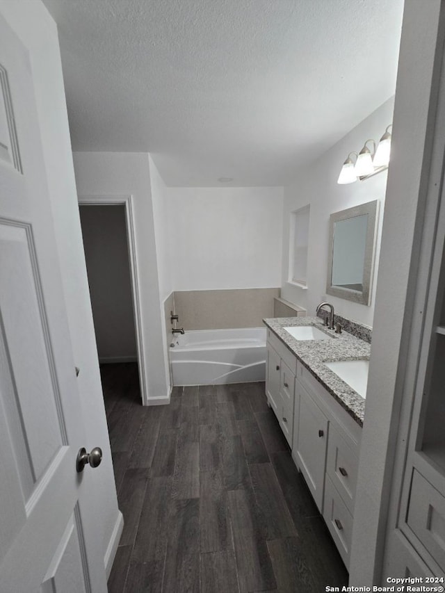 bathroom with a washtub, a textured ceiling, vanity, and hardwood / wood-style flooring