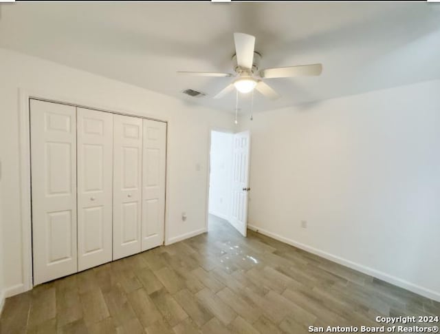 unfurnished bedroom featuring ceiling fan, a closet, and light hardwood / wood-style flooring