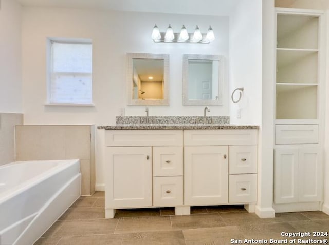 bathroom featuring a bathing tub, vanity, and tile patterned flooring