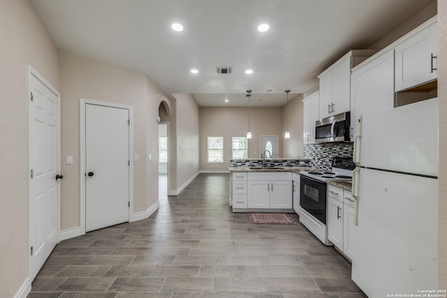 kitchen featuring sink, white cabinets, kitchen peninsula, hanging light fixtures, and white appliances