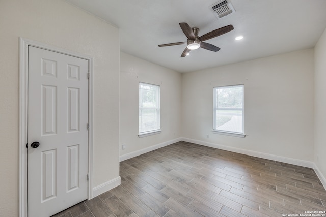 unfurnished room with a wealth of natural light, light hardwood / wood-style floors, and ceiling fan