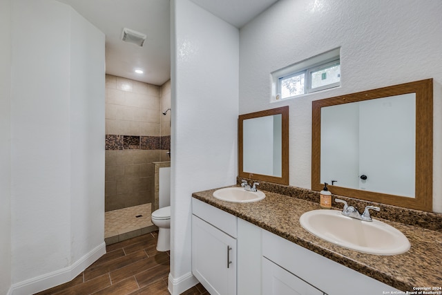 bathroom featuring a tile shower, vanity, and toilet