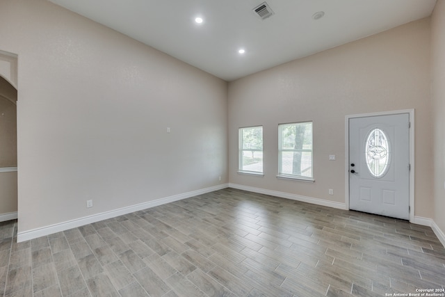 foyer entrance with light wood-type flooring and a towering ceiling