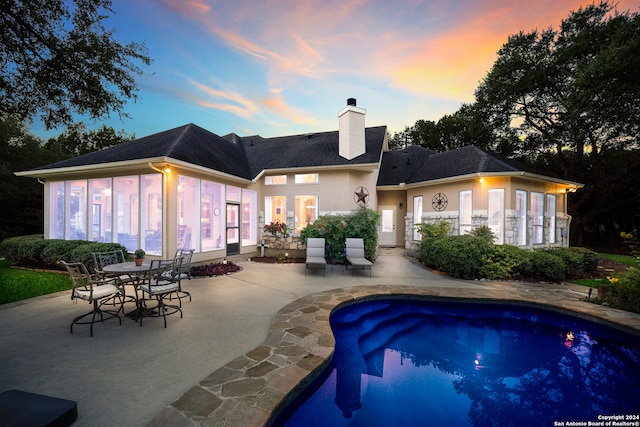 pool at dusk with a patio area