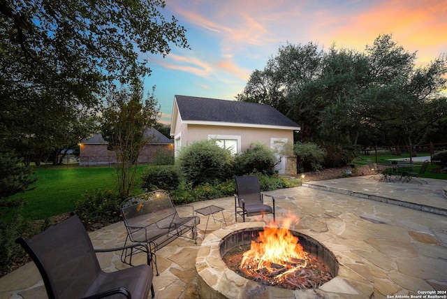 patio terrace at dusk with a lawn and an outdoor fire pit