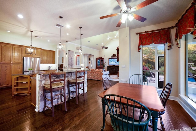dining room with visible vents, ceiling fan, arched walkways, dark wood-style floors, and vaulted ceiling