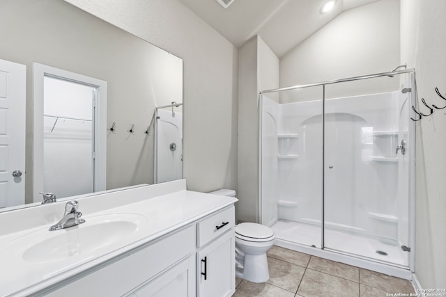 bathroom featuring vanity, a shower with door, vaulted ceiling, tile patterned flooring, and toilet