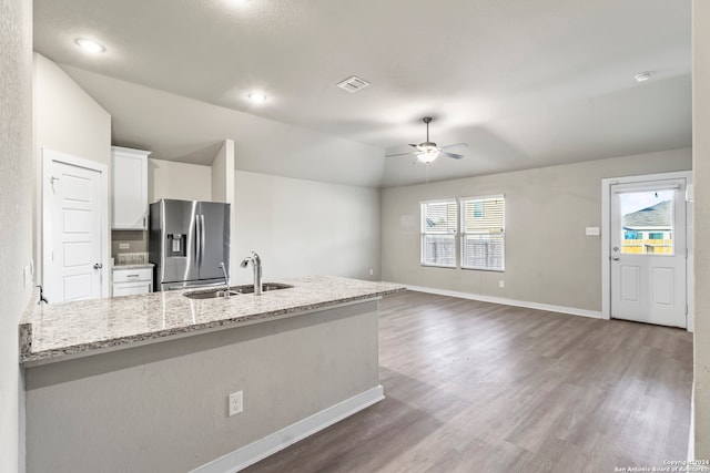 kitchen featuring a wealth of natural light, stainless steel fridge, sink, and white cabinets