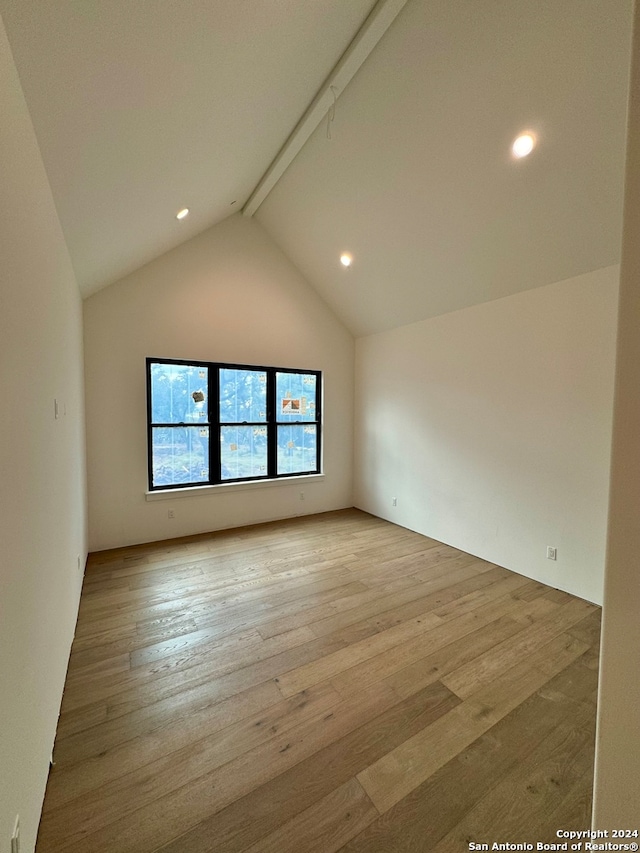 empty room with lofted ceiling with beams and light hardwood / wood-style flooring