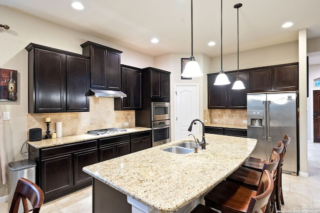 kitchen featuring stainless steel appliances, sink, a center island with sink, and backsplash