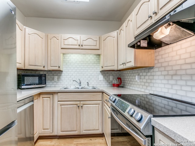 kitchen with sink, appliances with stainless steel finishes, light hardwood / wood-style floors, and decorative backsplash