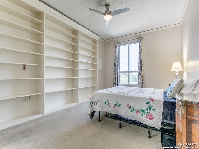 carpeted bedroom with ornamental molding, ceiling fan, and a textured ceiling