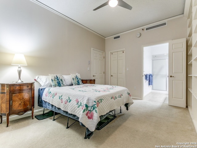 bedroom with crown molding, light carpet, ceiling fan, and a closet