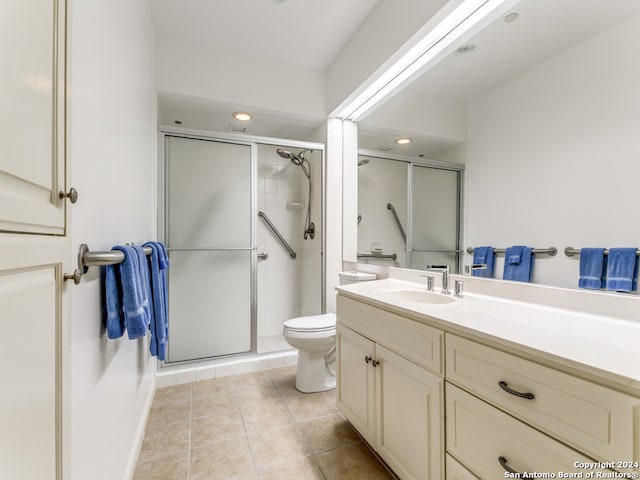 bathroom featuring a shower with door, toilet, vanity, and tile patterned floors