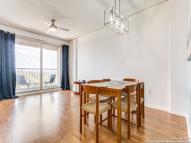 dining space with a textured ceiling, ceiling fan with notable chandelier, and light wood-type flooring