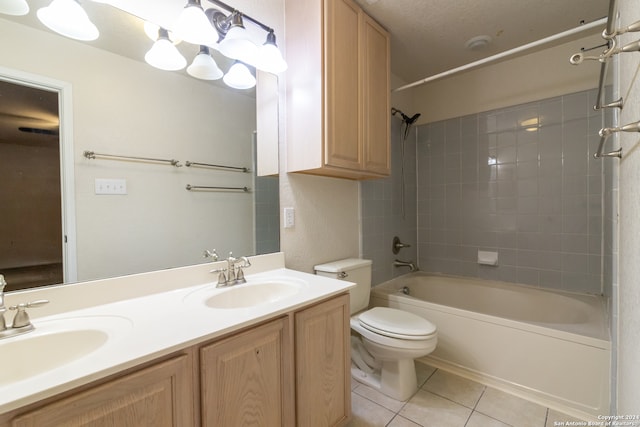 full bathroom featuring tile patterned flooring, a textured ceiling, tiled shower / bath, vanity, and toilet