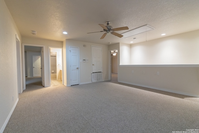 unfurnished bedroom with a textured ceiling, ceiling fan, light carpet, and ensuite bathroom