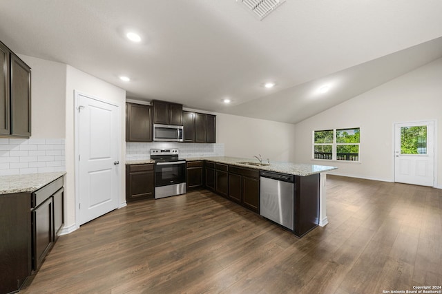 kitchen featuring sink, kitchen peninsula, dark wood-type flooring, appliances with stainless steel finishes, and vaulted ceiling