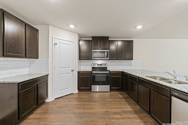 kitchen featuring dark hardwood / wood-style flooring, stainless steel appliances, light stone counters, and sink