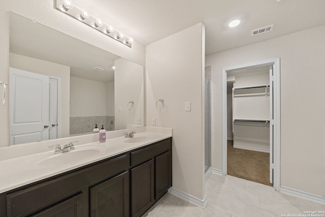 bathroom featuring a textured ceiling, a shower with door, vanity, and tile patterned floors