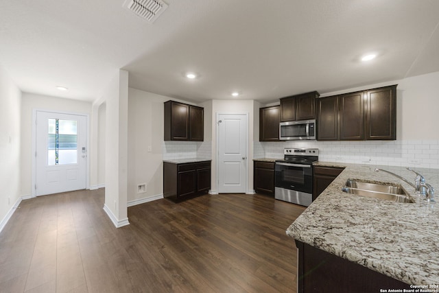 kitchen featuring appliances with stainless steel finishes, backsplash, sink, and dark wood-type flooring