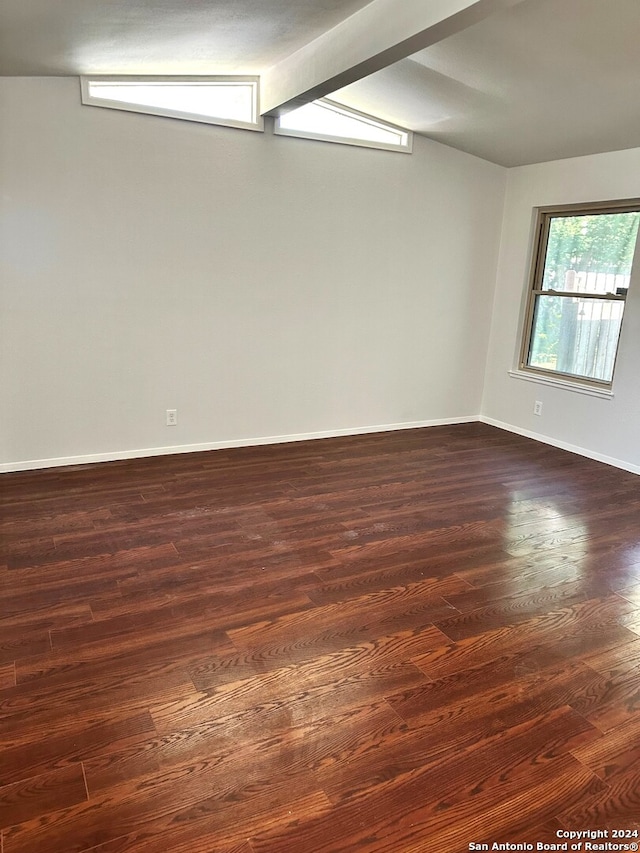 spare room featuring beamed ceiling and dark hardwood / wood-style floors