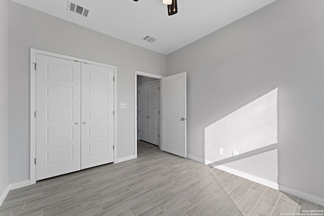 unfurnished bedroom with light hardwood / wood-style floors, ceiling fan, and a closet