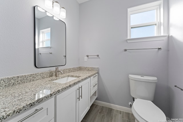 bathroom with a healthy amount of sunlight, vanity, toilet, and hardwood / wood-style floors