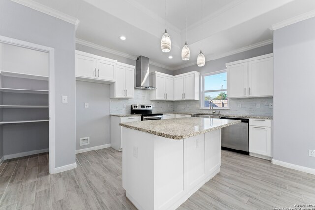 kitchen featuring light wood-type flooring, white cabinetry, a kitchen island, wall chimney range hood, and appliances with stainless steel finishes