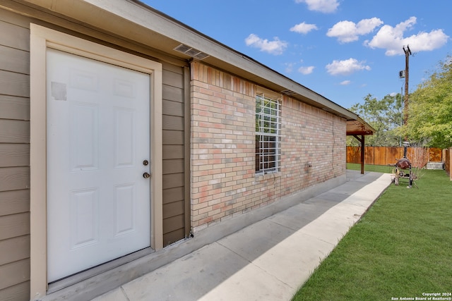 property entrance featuring a lawn and a patio