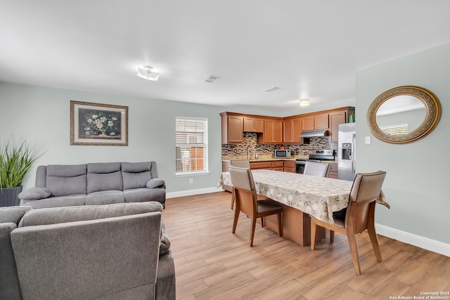 dining space with light wood-type flooring and sink