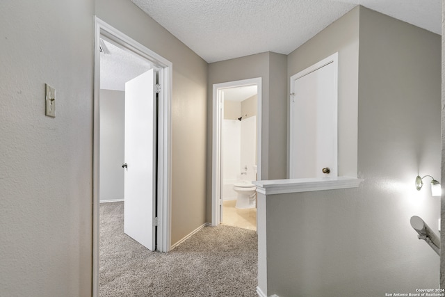 hallway with a textured ceiling and light colored carpet