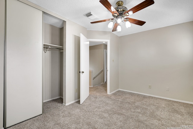 unfurnished bedroom with ceiling fan, light colored carpet, a textured ceiling, and a closet