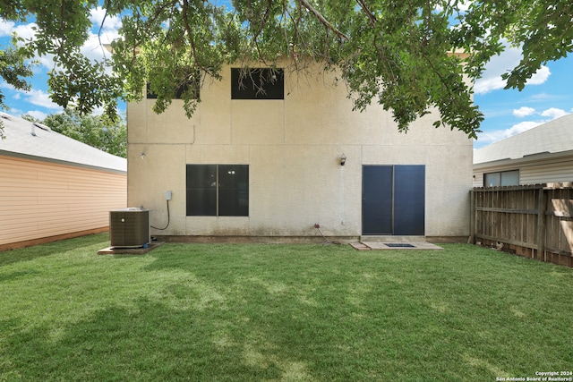 rear view of house with a lawn and central AC