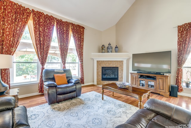 living room featuring a tile fireplace, light hardwood / wood-style flooring, and a wealth of natural light