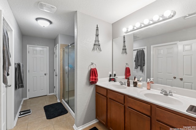 bathroom with vanity, a textured ceiling, an enclosed shower, and tile patterned floors